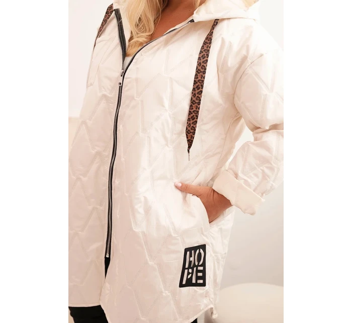 Dámská bunda Plus Size prošívaná s kapucí a nápisem model 21229239 světlé béžové - K-Fashion Dámská bunda Plus Size prošívaná s kapucí a nápisem model 21229239 světlé béžové - K-Fashion