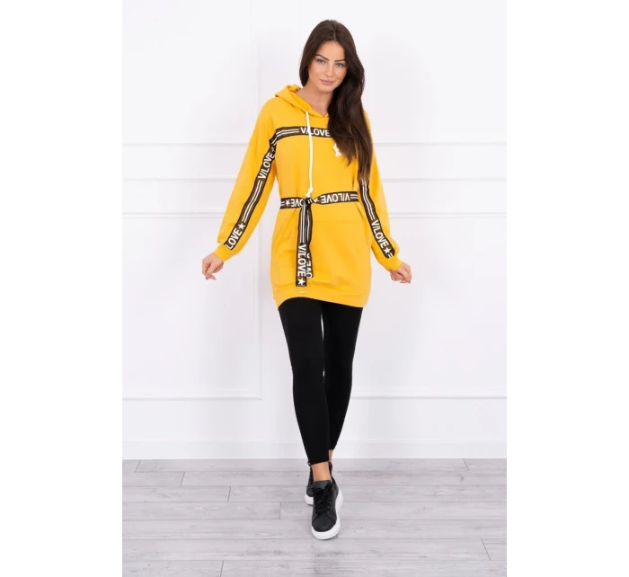 Šaty zdobené stuhou a nápisy v hořčicové barvě Šaty zdobené stuhou a nápisy v hořčicové barvě