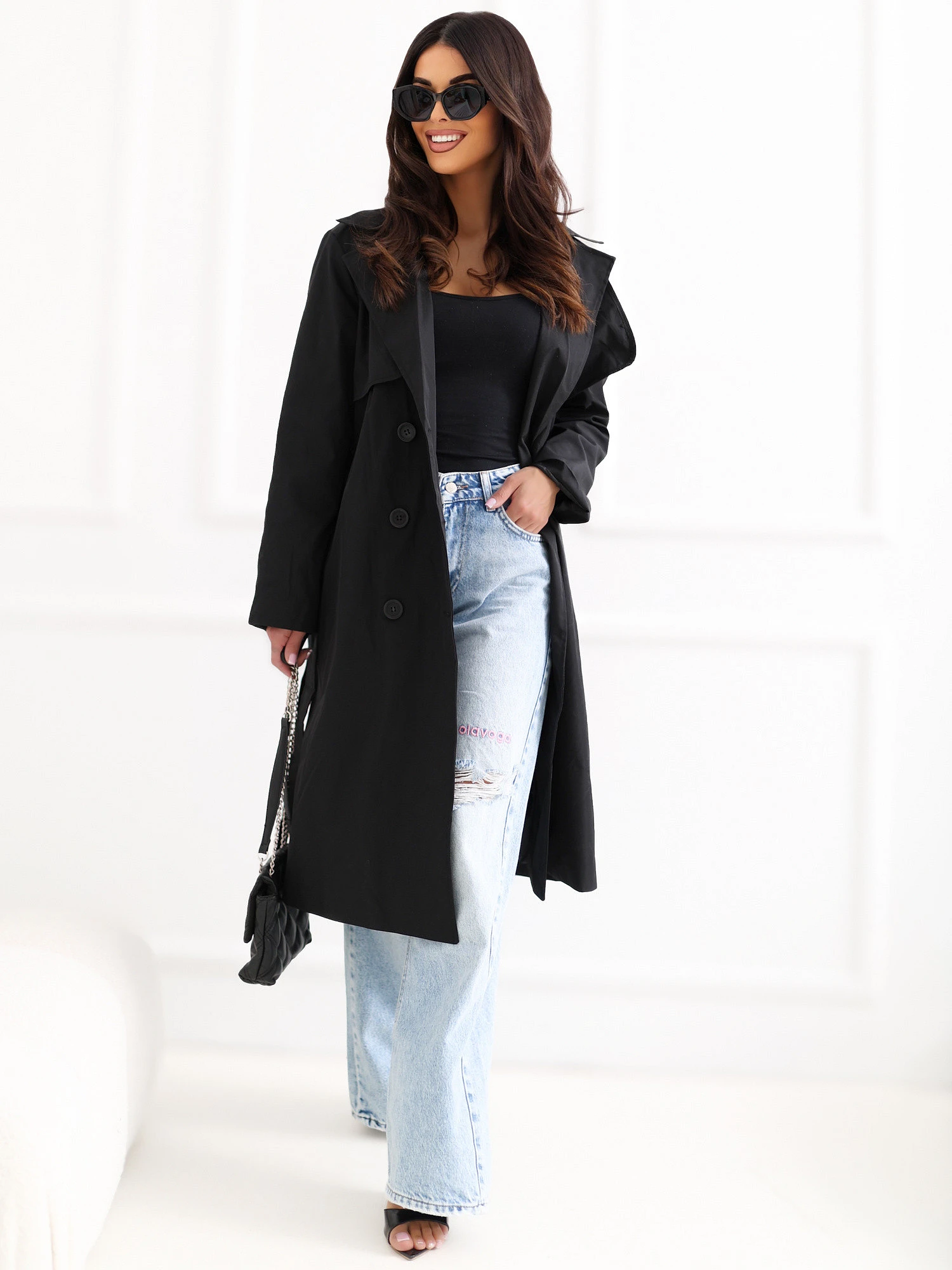 Woman in black trench coat with jeans and heels casual festive