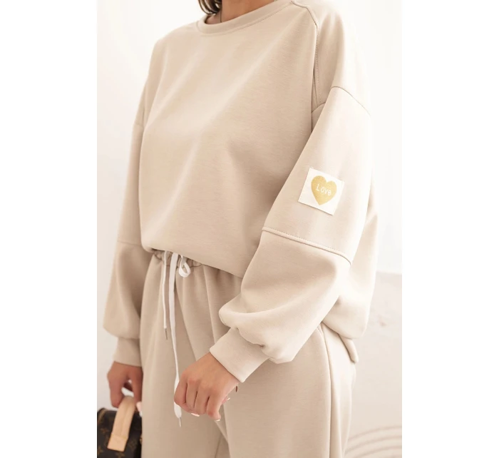 Dámský komplet model 21285327 s volnou mikinou a kalhotami s nápisem LOVE béžový - K-Fashion Dámský komplet model 21285327 s volnou mikinou a kalhotami s nápisem LOVE béžový - K-Fashion